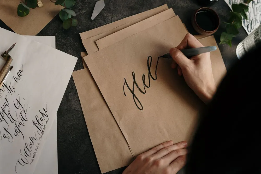 Calligrapher writing on brown paper with ink and pen