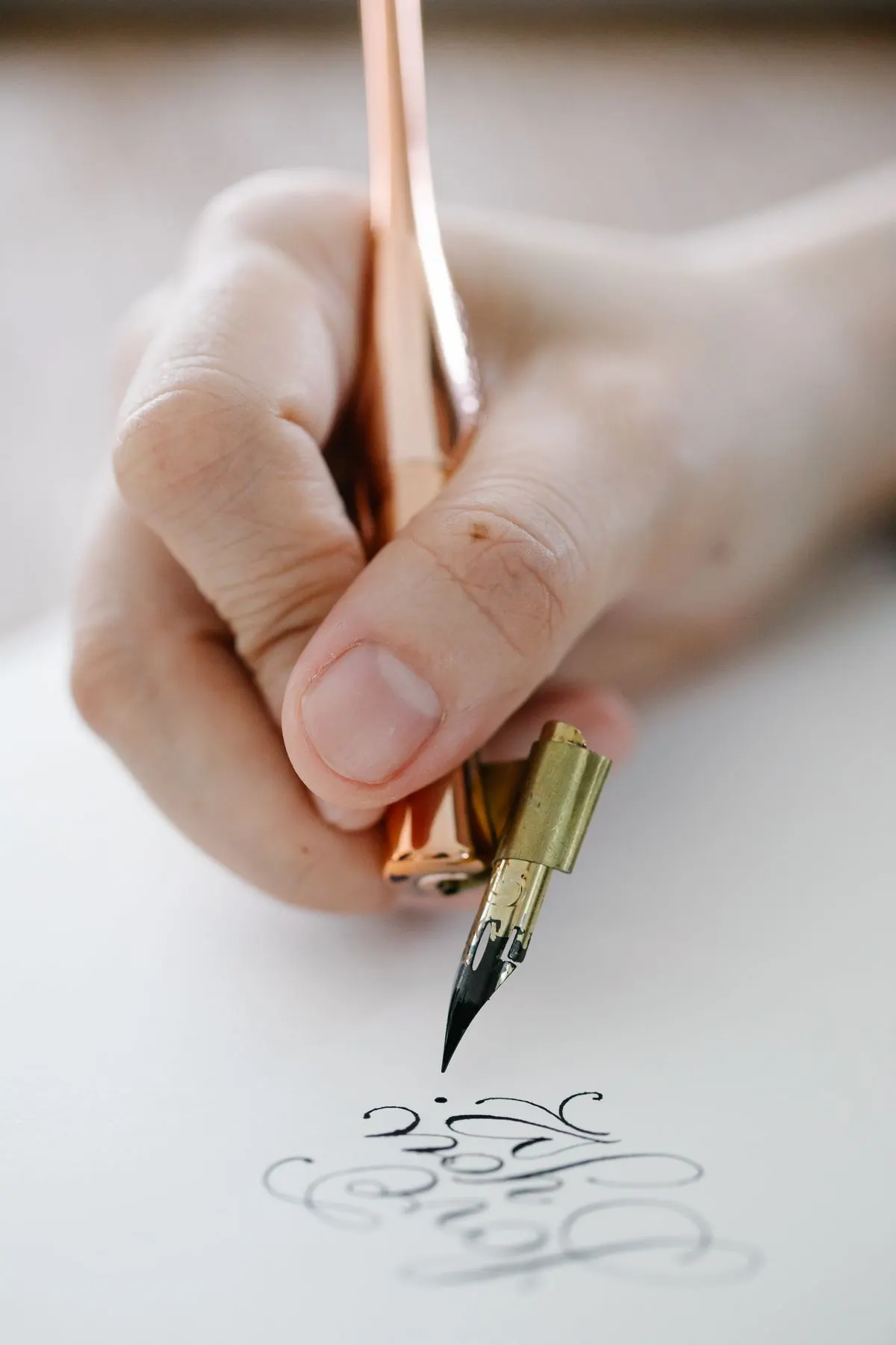 Close up of a hand writing calligraphy with a dip pen