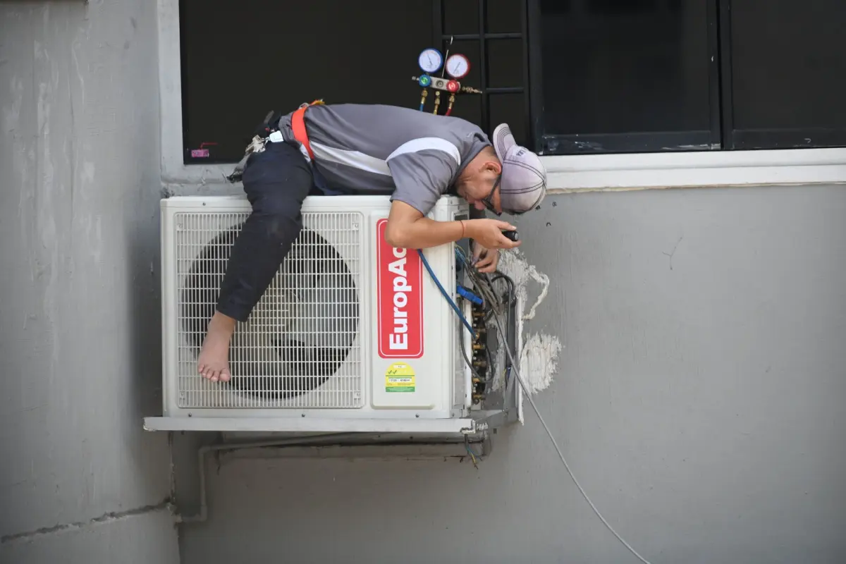 Technician cleaning a wall-mounted air conditioning unit