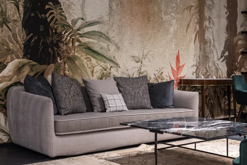 Sofa with pillows against a wall painted with leaves