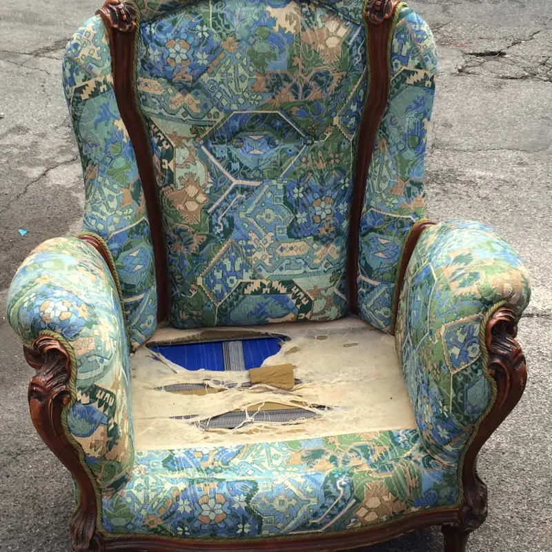 Old armchair with a torn seat, ready for restoration