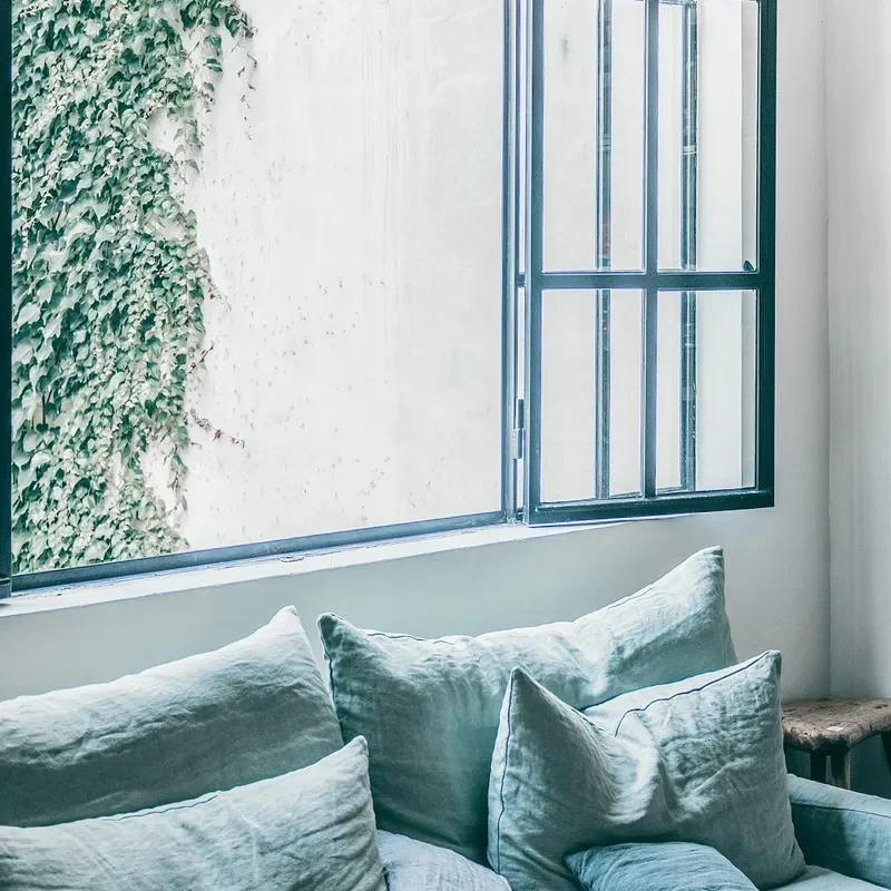 Blue couch with cushions beside an open window